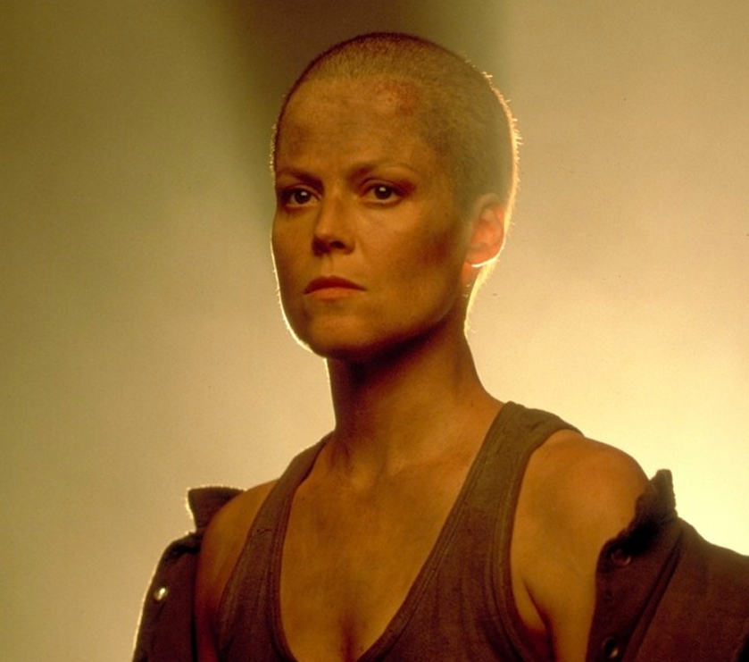 Ripley Sigourney Weaver in Aliens 3 with a shaved head and intense expression wearing a sleeveless top and jacket